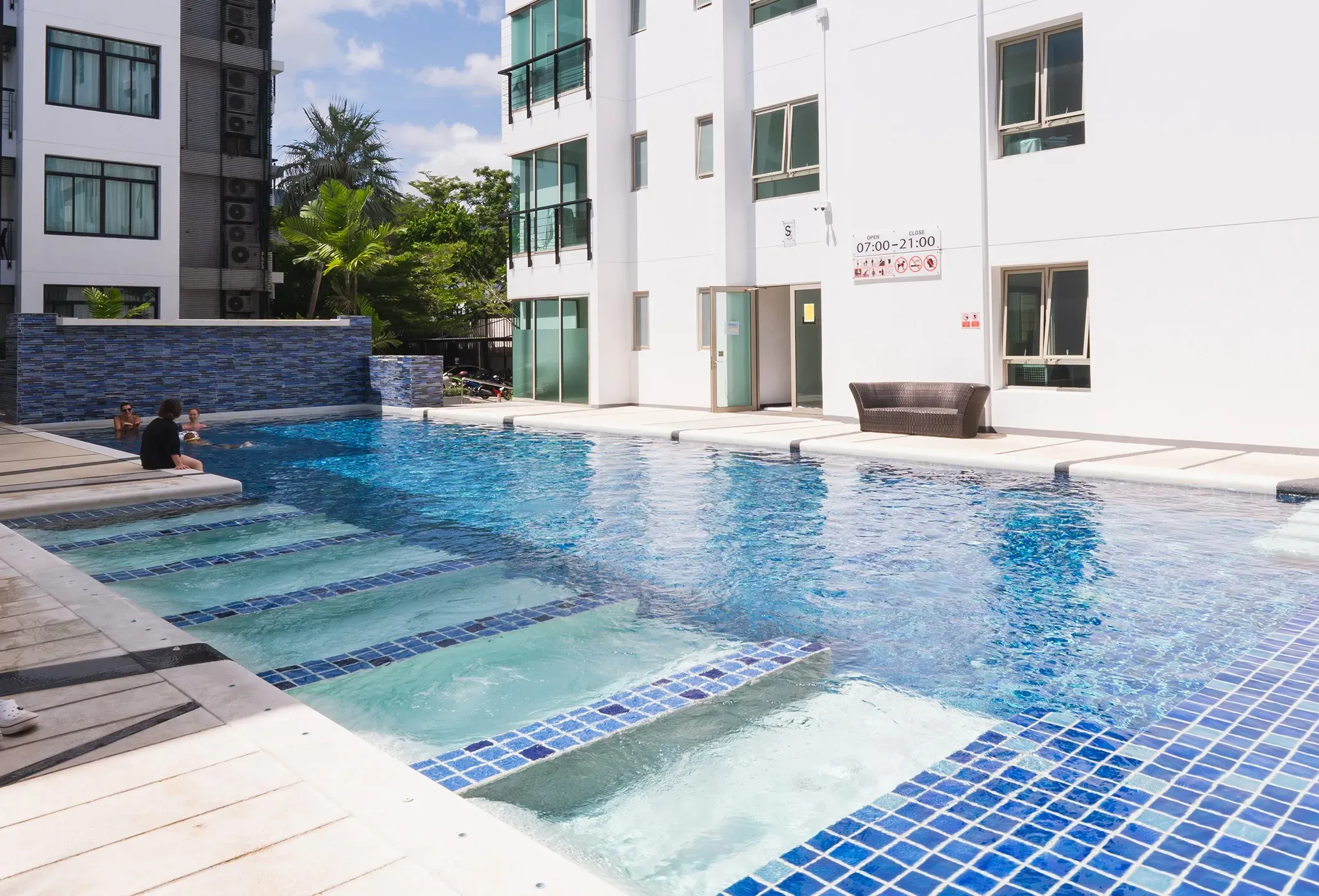 Modern exterior of the white condominium buildings with the blue-tiled swimming pool